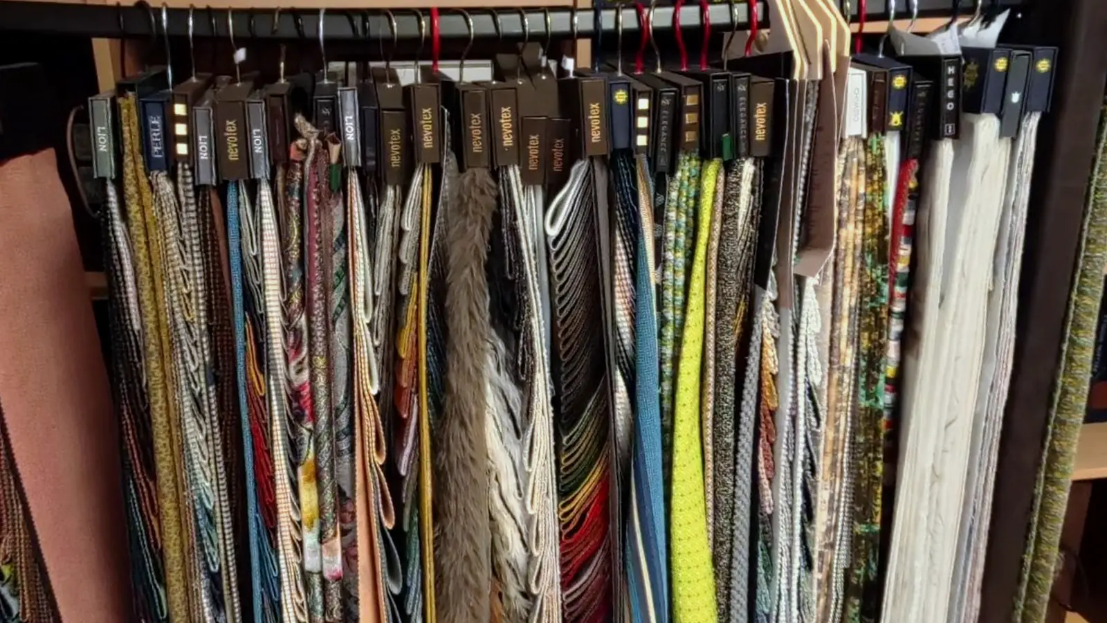 Stoffbibliothek im Showroom: dicht gehängte Musterfahnen in vielen Farben und Strukturen an einer Stange